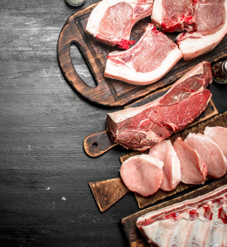 The Pork variety bundle from winterscattleranch features assorted Berkshire pork cuts, like chops and ribs, beautifully displayed on wooden boards atop a dark wood surface.