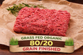 A portion of winterscattleranch 80/20 Grass-Fed/Organic Grain Finished Ground Beef rests on parchment with rosemary. A label reads: Grass-Fed Organic, 80/20, Grain Finished. Available in bundles from 5 to 60 lbs.