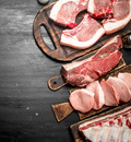 Thick slices of raw, marbled pork from the winterscattleranch Organic care Pork Bundle - 25 lbs Subscription are arranged on wooden boards, ready for home delivery and perfect for premium meal prep.